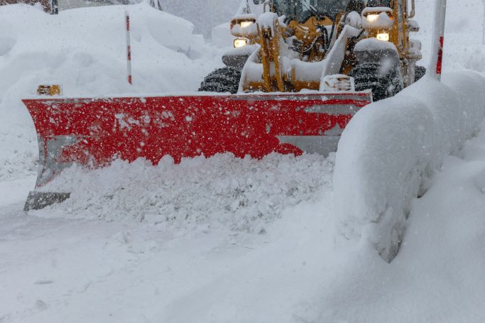 Schneeräumfahrzeug räumt frischen Schnee von einer Straße.