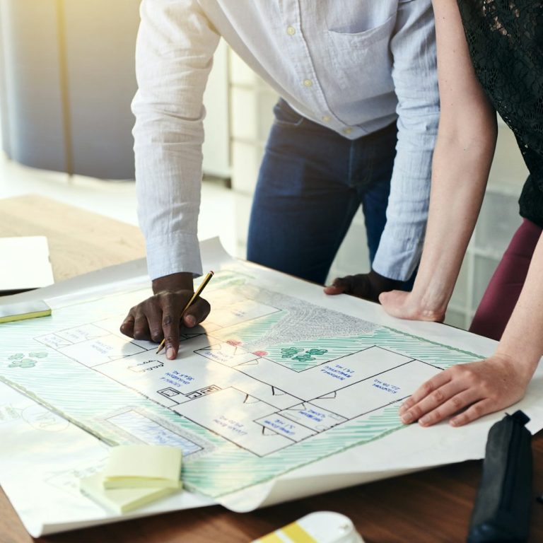 Zwei Planer betrachten und markieren einen Plan auf einem Planungstisch